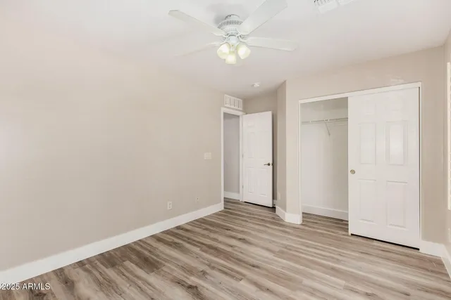 an empty room with wooden floor and fan
