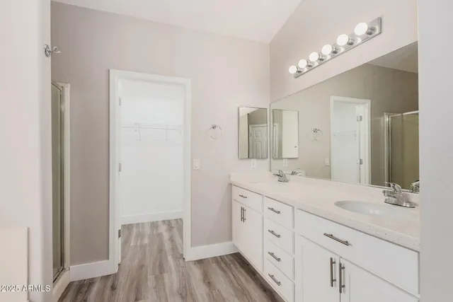 a spacious bathroom with a double vanity sink a mirror and a shower