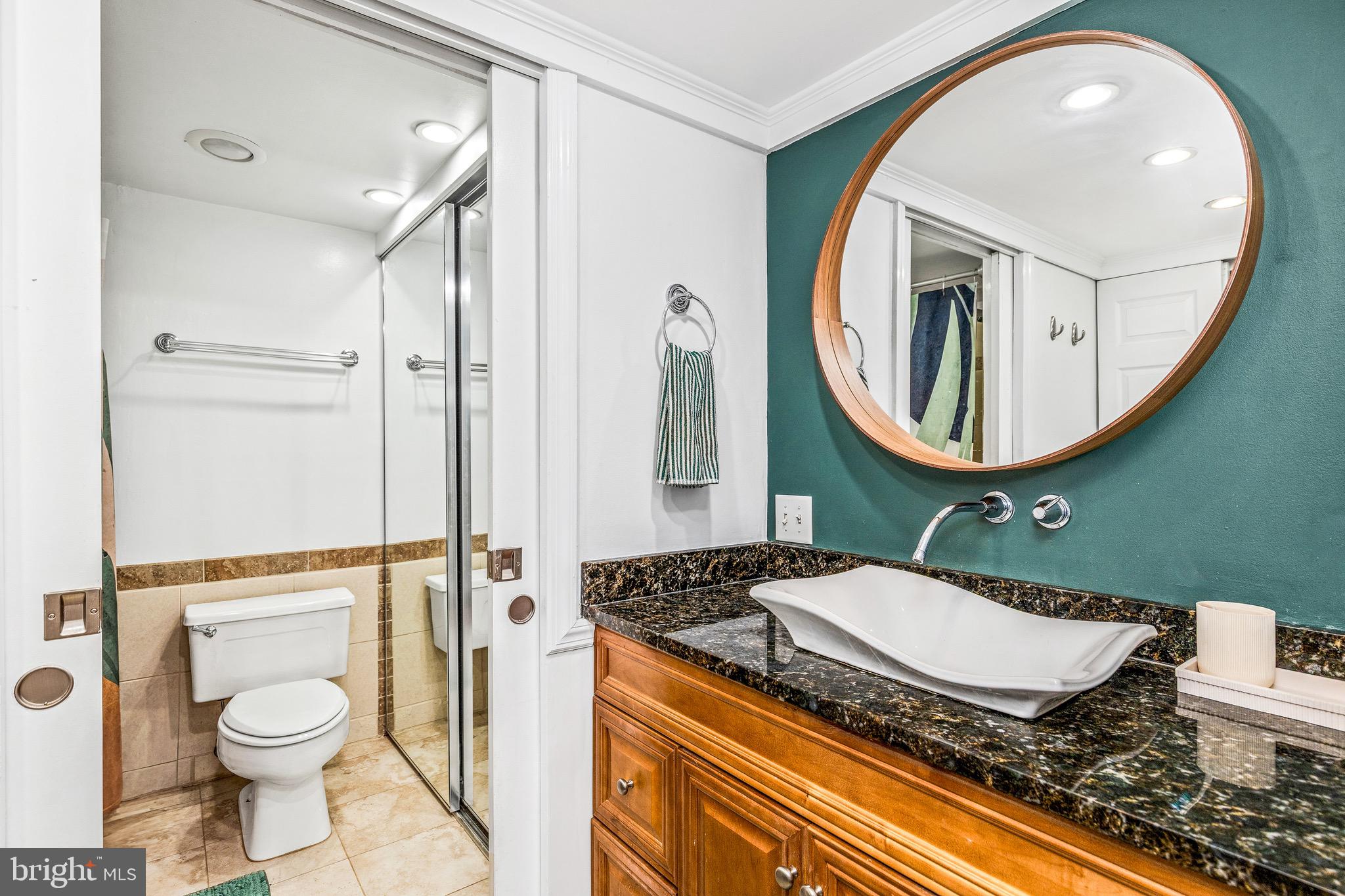 1001 26th Street Northwest, Unit 306 Washington, DC 20037 - Photo 14 of 22 a bathroom with a granite countertop toilet sink and mirror