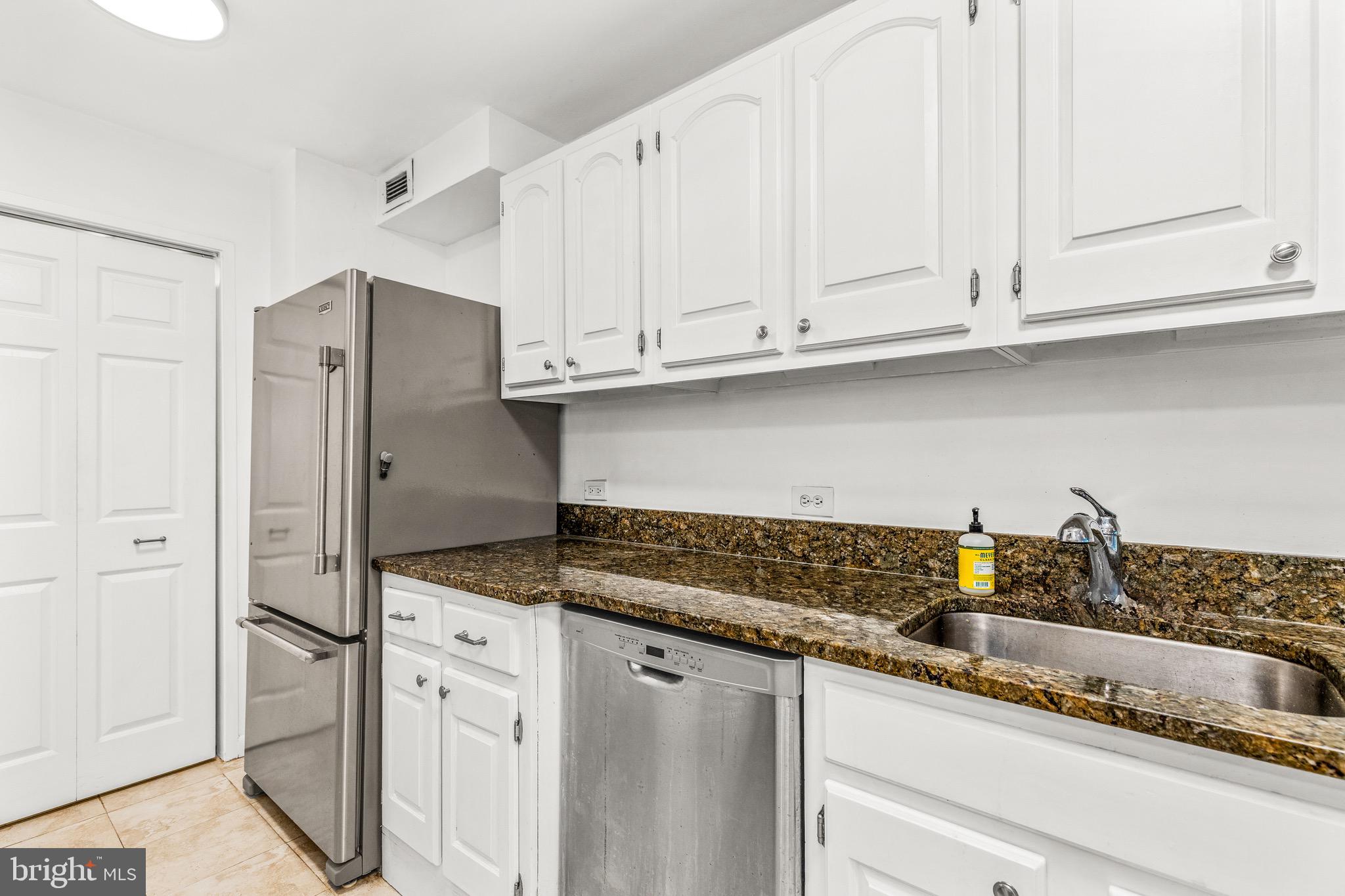 1001 26th Street Northwest, Unit 306 Washington, DC 20037 - Photo 9 of 22 a kitchen with stainless steel appliances granite countertop a refrigerator and white cabinets