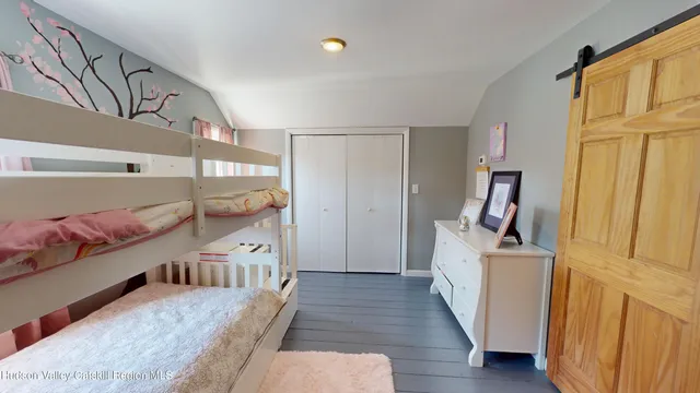 a view of a hallway to a livingroom with wooden floor and furniture