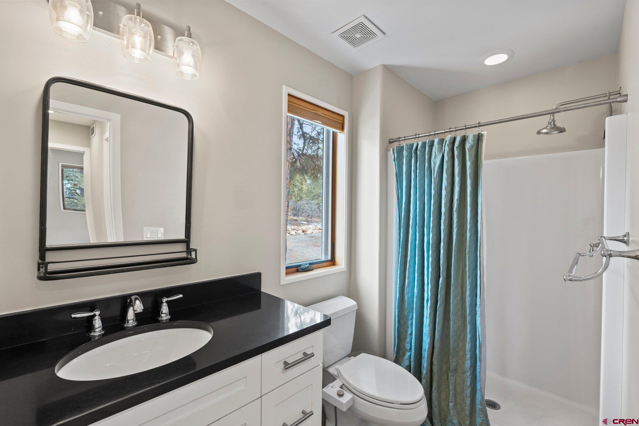 855 Ridge Road Durango, CO 81303 - Photo 17 of 35 a bathroom with a granite countertop sink toilet a mirror a vanity and shower