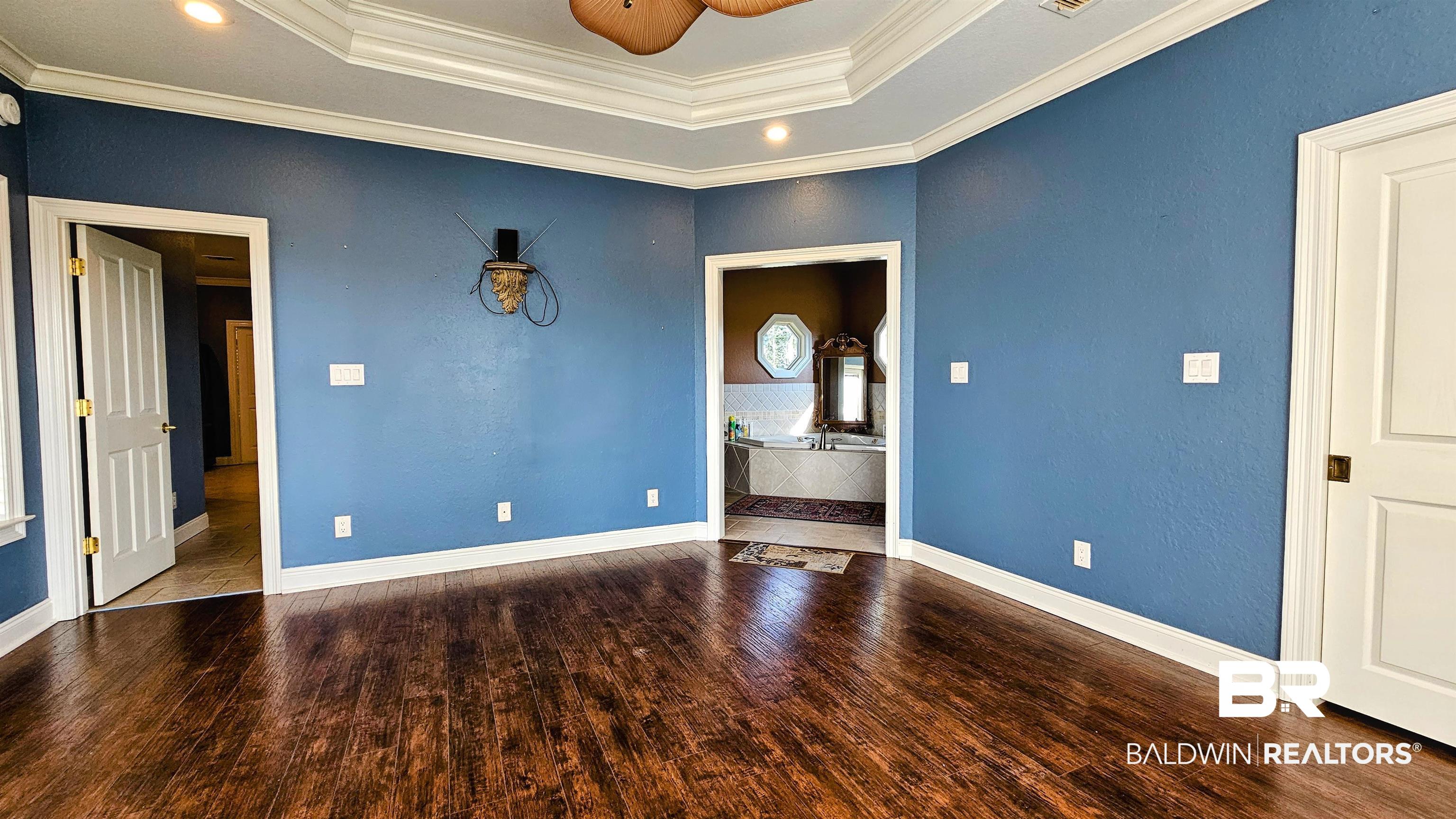 9275 Crawford Road Elberta, AL 36530 - Photo 12 of 28 Unfurnished bedroom featuring ornamental molding, wood finished floors, recessed lighting, a tray ceiling, and a ceiling fan