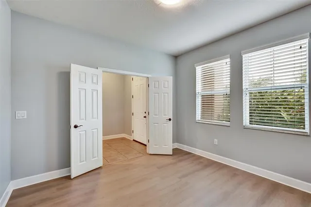 an empty room with wooden floor and windows