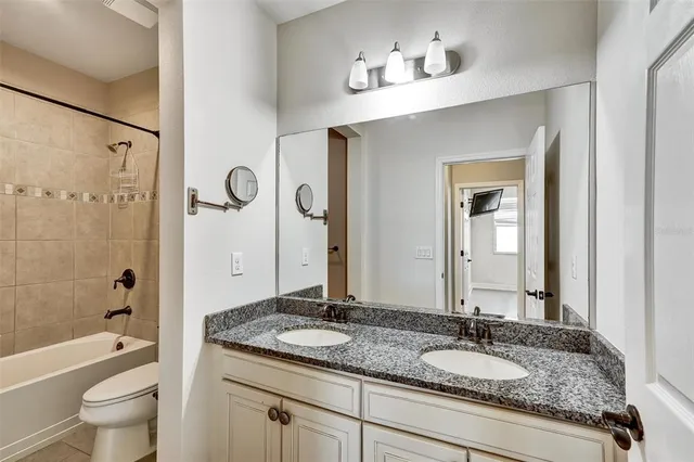 a bathroom with a granite countertop sink toilet mirror and shower