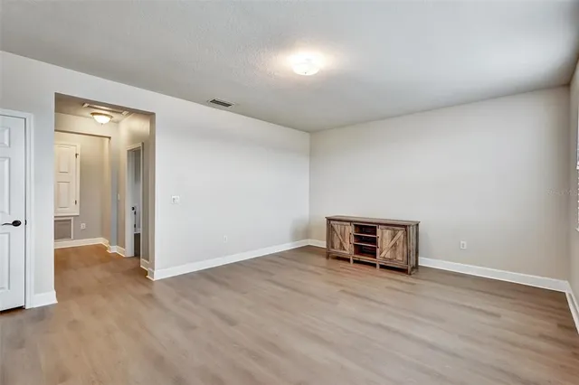 an empty room with wooden floor and mirror