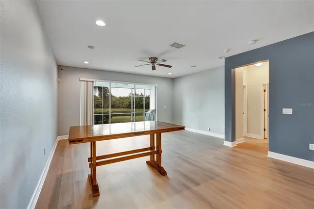 an empty room with wooden floor and a ceiling fan