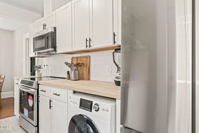 a utility room with stainless steel appliances granite countertop a refrigerator and a sink