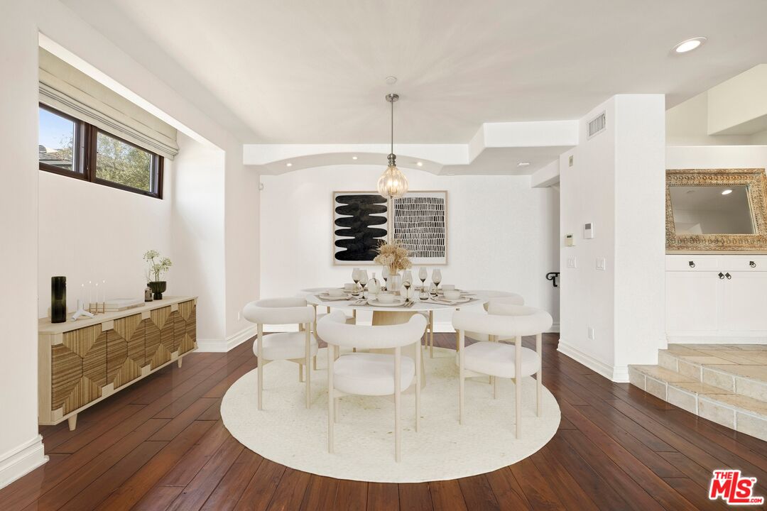 849 14th Street, Unit 8 Santa Monica, CA 90403 - Photo 3 of 19 a dining room with wooden floor a chandelier a wooden table and chairs