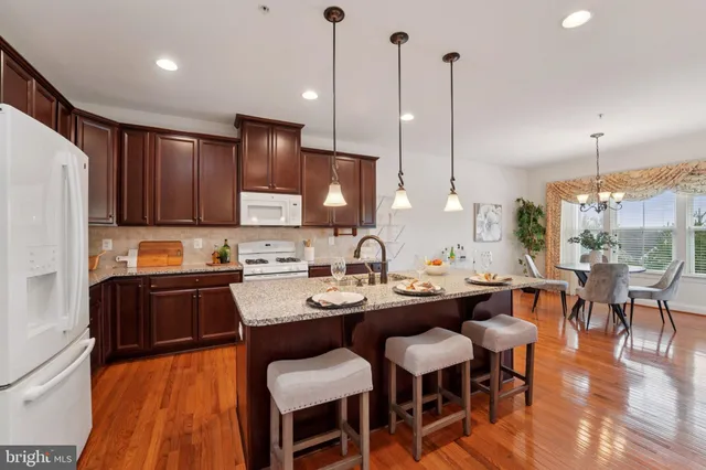 a kitchen with stainless steel appliances granite countertop a sink a stove a refrigerator and island with wooden floor