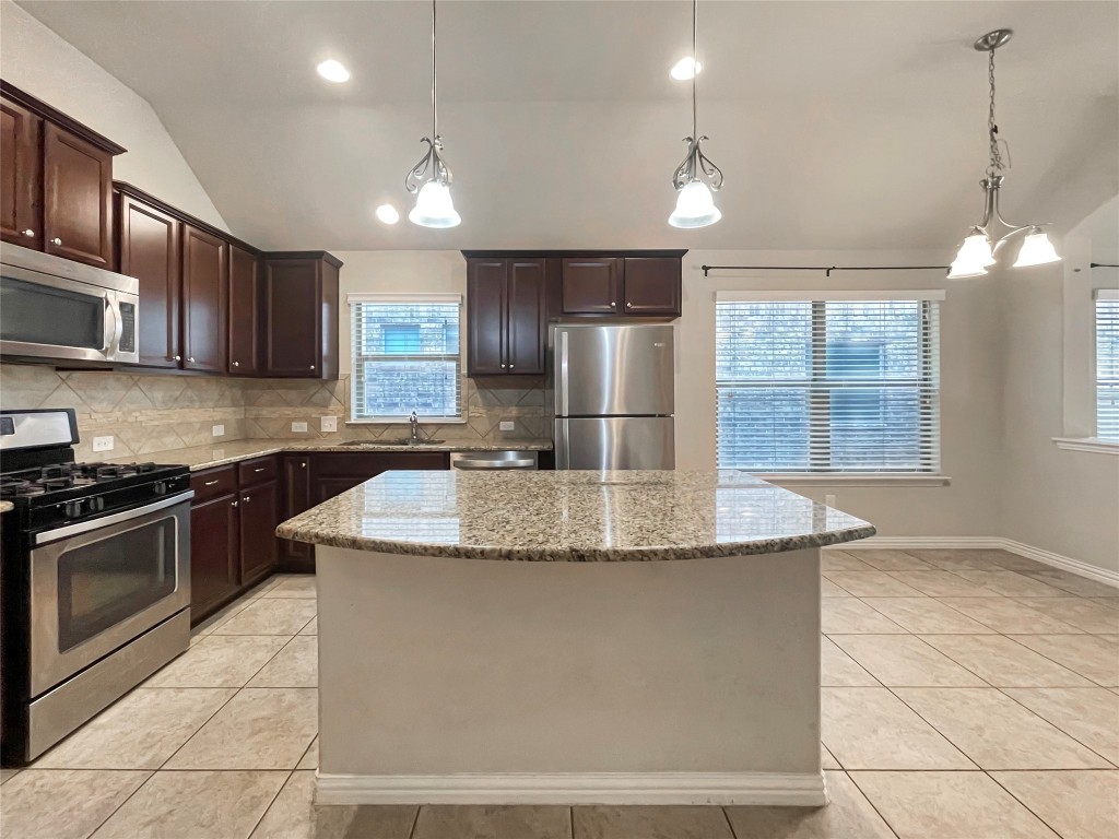 2468 Millbrook Loop Leander, TX 78641 - Photo 6 of 16 a kitchen with stainless steel appliances granite countertop a sink a stove a microwave and island