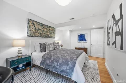 a spacious bedroom with a bed and wooden floor