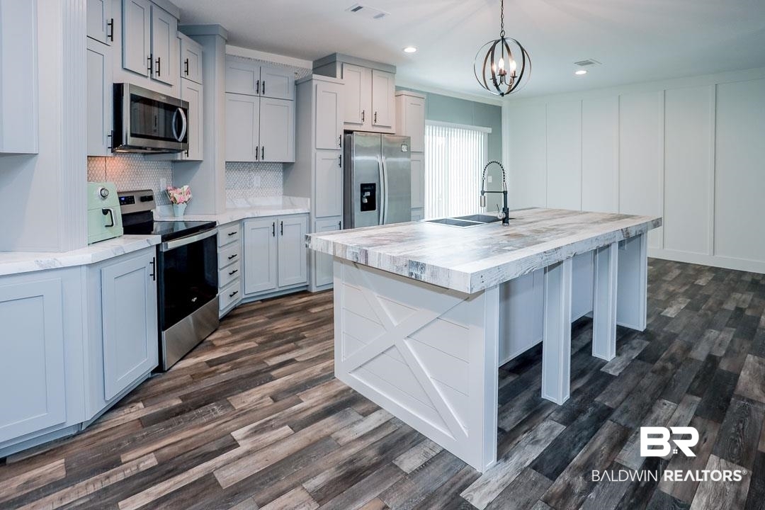 19180 Horseshoe Circle Seminole, AL 36574 - Photo 7 of 38 Kitchen featuring appliances with stainless steel finishes, a breakfast bar, tasteful backsplash, pendant lighting, and dark wood-style floors