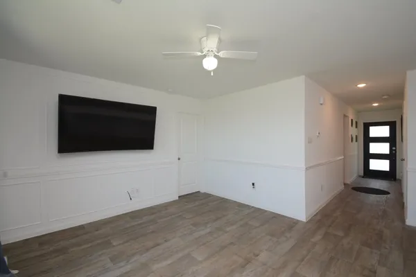 a view of a livingroom with an empty space a ceiling fan and windows