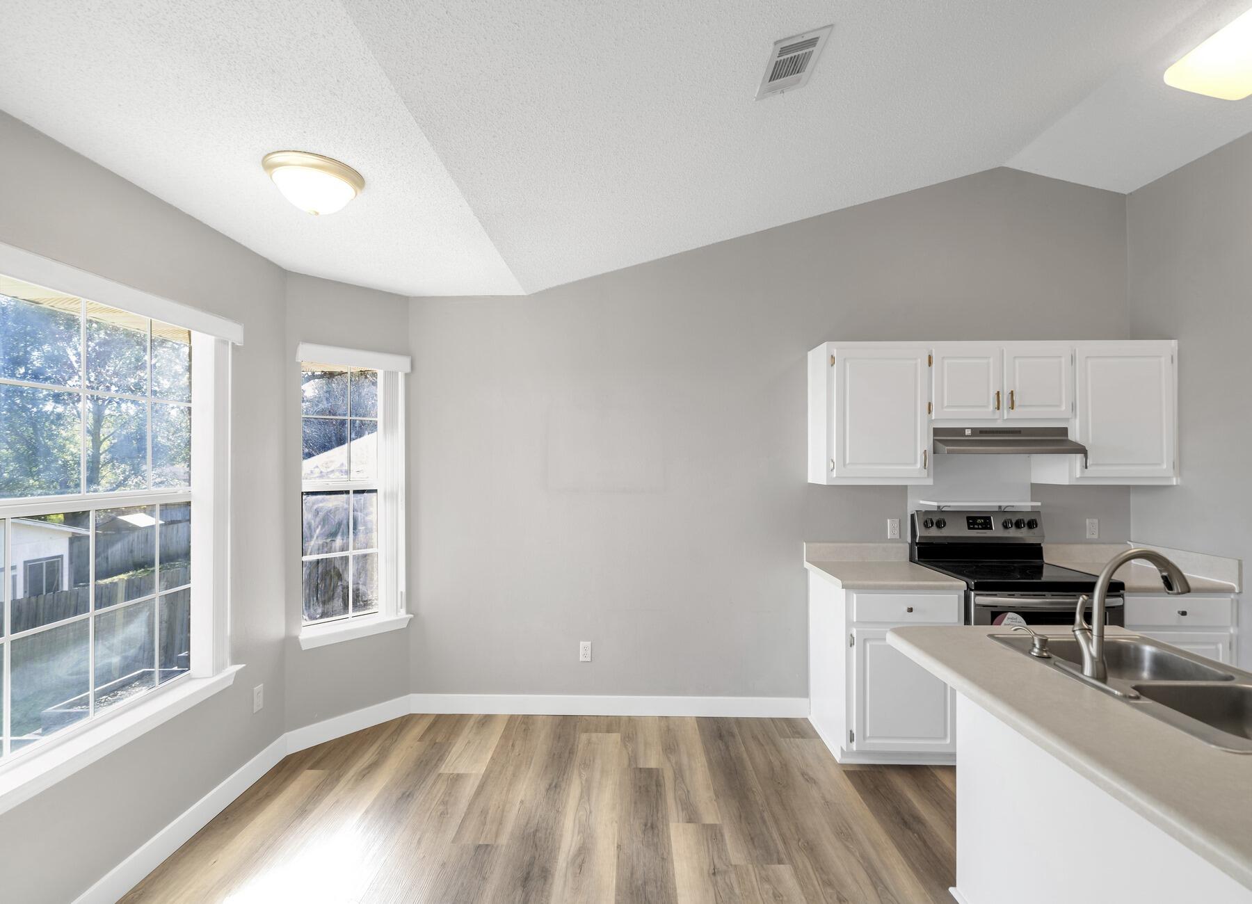 5130 Whitehurst Lane Crestview, FL 32536 - Photo 14 of 49 a kitchen with granite countertop a stove a sink a refrigerator and white cabinets with wooden floor