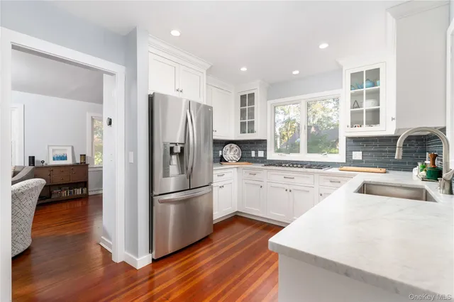 a kitchen with stainless steel appliances granite countertop a refrigerator a sink dishwasher a stove and white cabinets with wooden floor