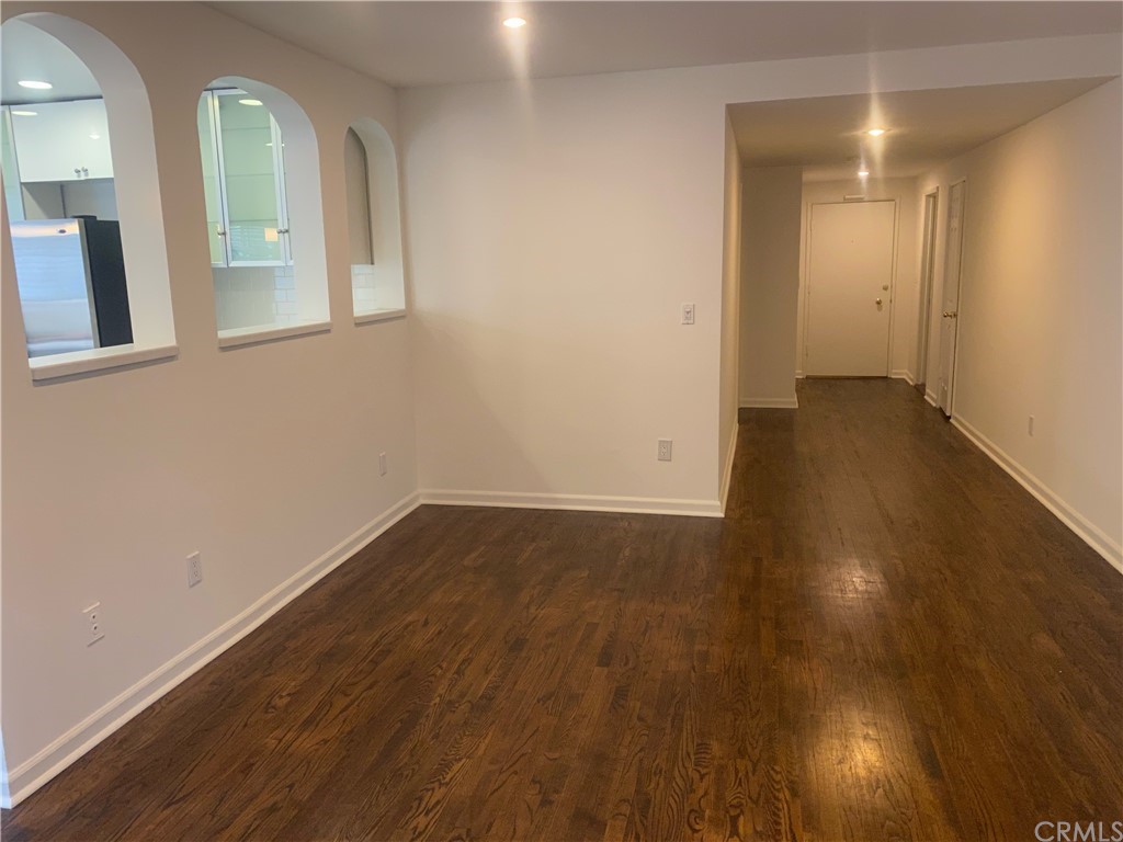 11767 Sunset Boulevard, Unit 202 Los Angeles, CA 90049 - Photo 6 of 23 an empty room with wooden floor and windows