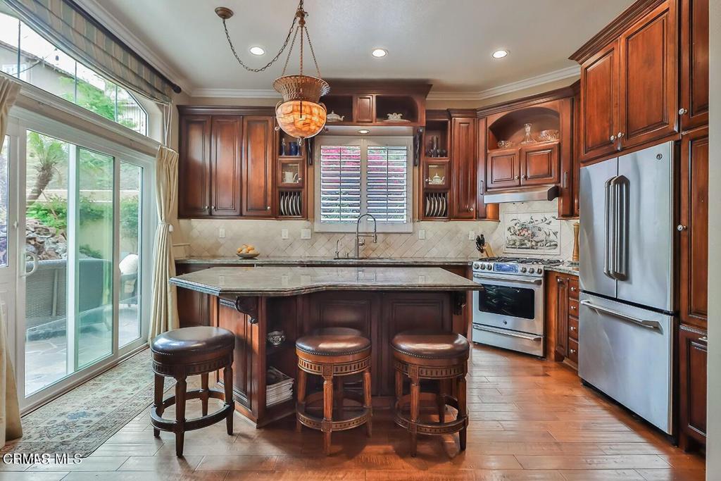 963 Corte Augusta Camarillo, CA 93010 - Photo 10 of 27 a kitchen with stainless steel appliances granite countertop a stove a refrigerator a sink dishwasher a dining table and chairs with wooden floor