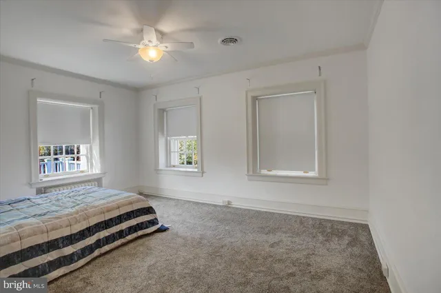 a spacious bedroom with a bed a chandelier and a dresser