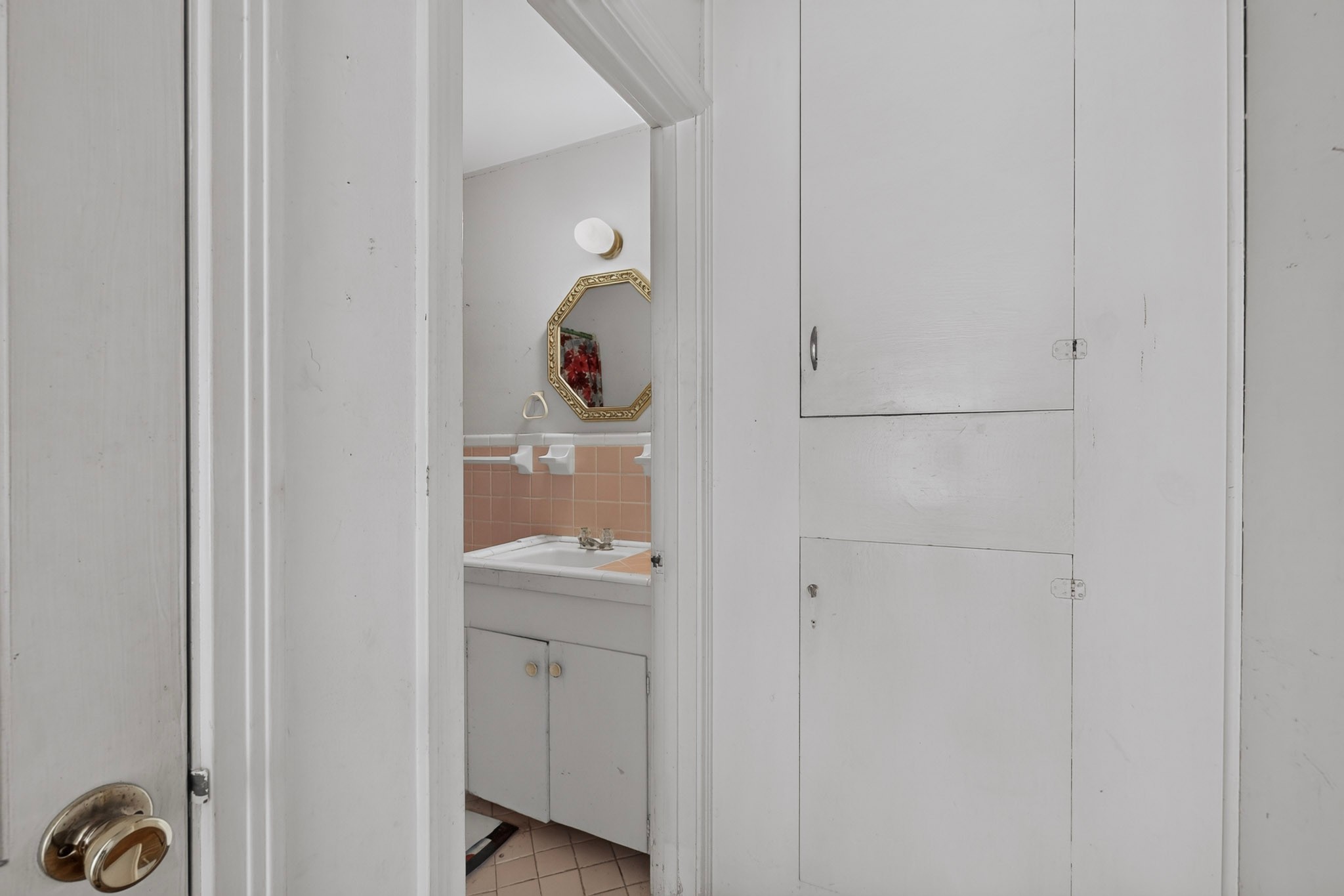 4703 Leslie Avenue Austin, TX 78721 - Photo 13 of 34 A well-lit bathroom features classic pink tile accents and practical vanity storage.