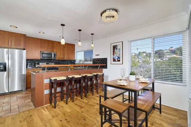 a kitchen with stainless steel appliances a dining table chairs stove and refrigerator