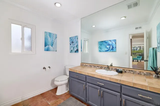 a bathroom with a granite countertop sink a toilet and a large mirror