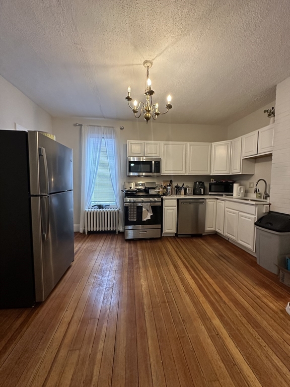 47 Wallingford Road, Unit 1 Boston, MA 02135 - Photo 3 of 16 a kitchen with stainless steel appliances granite countertop a refrigerator a stove top oven a sink dishwasher and wooden floor