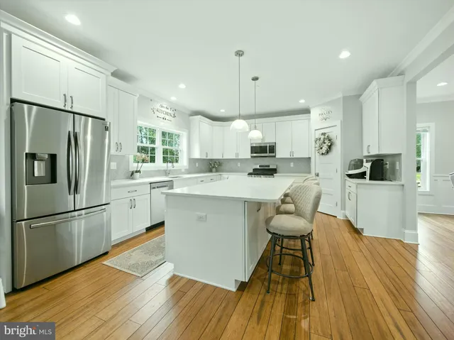 a kitchen with stainless steel appliances a refrigerator a stove a sink dishwasher and a refrigerator with wooden floor
