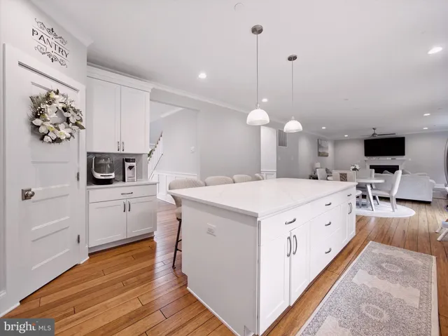 a large white kitchen with kitchen island a stove a sink a center island and wooden floor