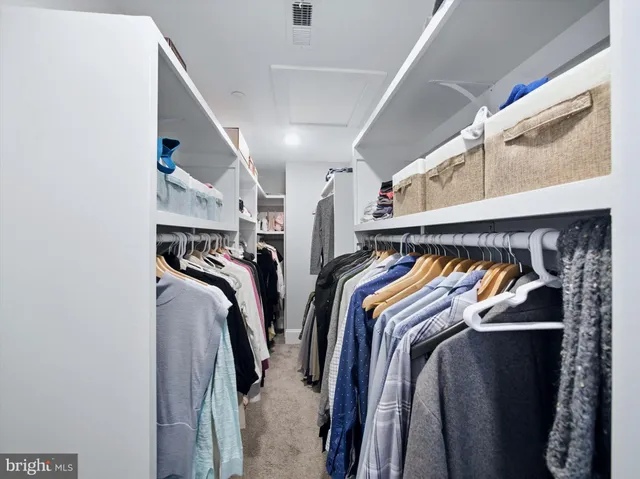 a view of walk in closet with clothes and shoes