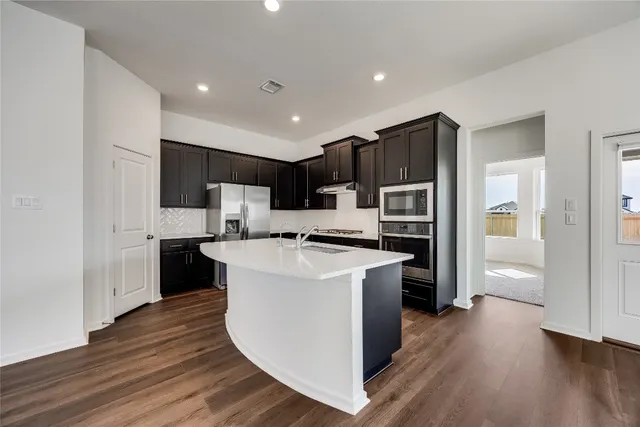 a kitchen with kitchen island stainless steel appliances a sink and refrigerator