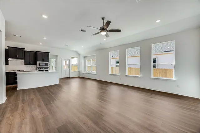 a view of an empty room with a window and wooden floor