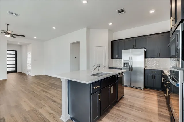 a kitchen with stainless steel appliances granite countertop a sink a refrigerator and a stove top oven