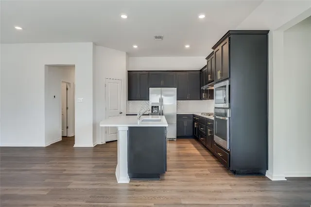a kitchen with stainless steel appliances a refrigerator and a stove top oven