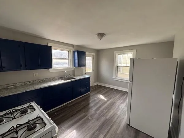 a large kitchen with wooden floor and cabinets