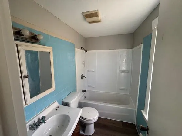 a bathroom with a bathtub shower sink vanity and toilet