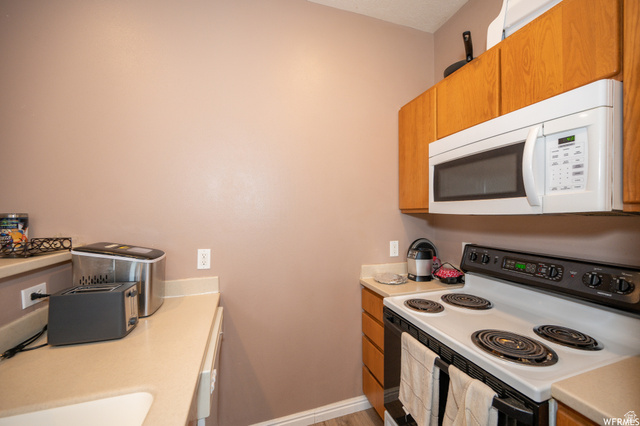 677 300 North, Unit 7 Provo, UT 84606 - Photo 5 of 16 Kitchen featuring wood cabinetry, solid surface countertops, and white appliances including an electric range and built-in microwave