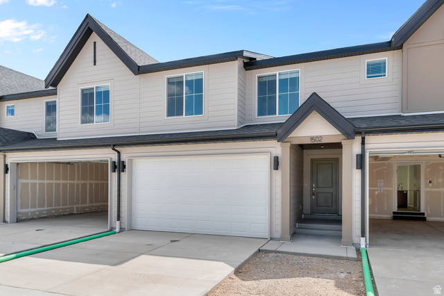 1907 East 640th North, Unit 1225 Salem, UT 84653 - Photo 12 of 20 Contemporary townhouse exterior featuring a covered entry, attached garage, two-story design, light-colored siding, and dark trim accents