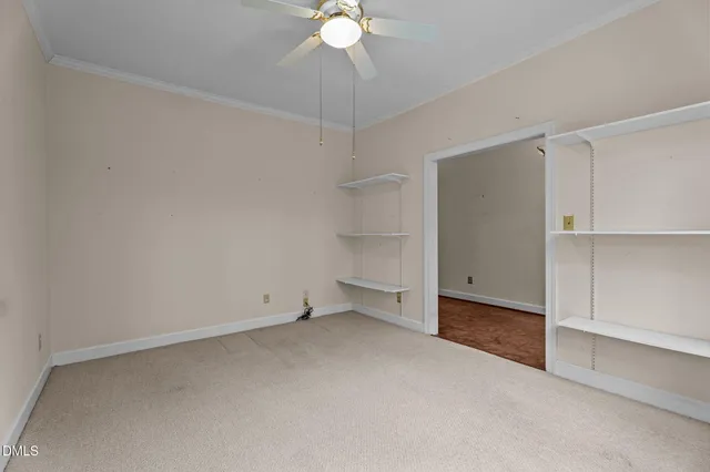 an empty room with a ceiling fan and carpet