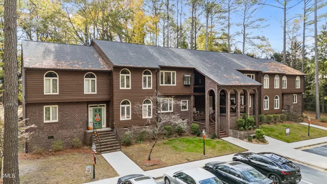 a view of a brick house with many windows and a tree
