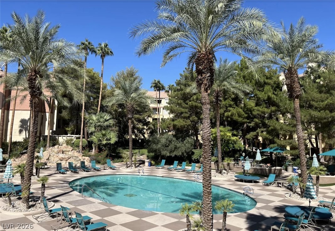 210 East Flamingo Road, Unit 137 Las Vegas, NV 89169 - Photo 1 of 32 An inviting pool area with ample lounge seating beneath swaying palm trees offers a tranquil escape.