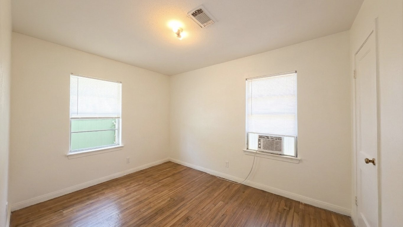 5879 Belneath Street Houston, TX 77033 - Photo 4 of 10 an empty room with wooden floor and windows