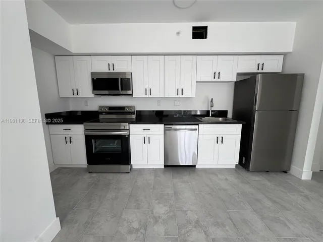 a kitchen with refrigerator and white cabinets
