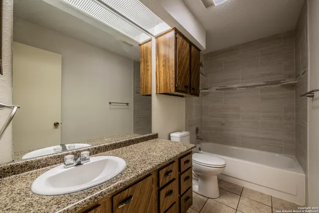 a bathroom with a granite countertop sink a toilet and bathtub
