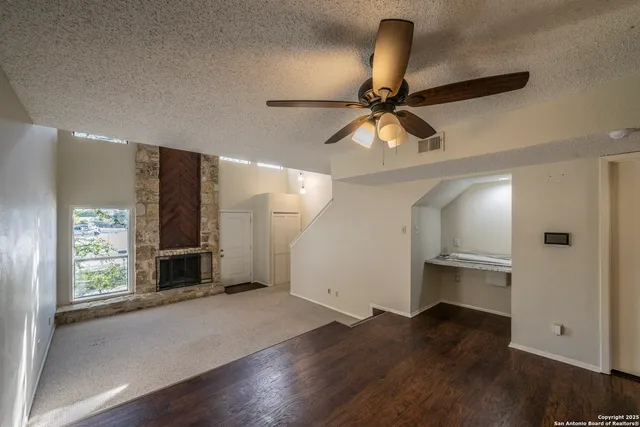 a view of empty room with wooden floor and fan
