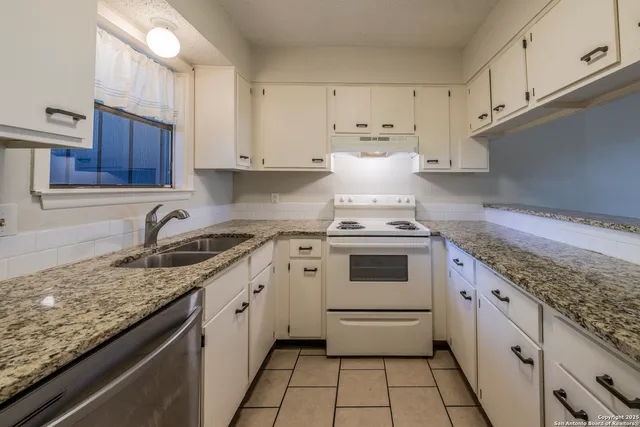 a kitchen with granite countertop white cabinets and white appliances