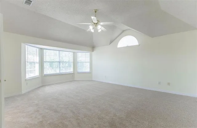 an empty room with chandelier fan and windows