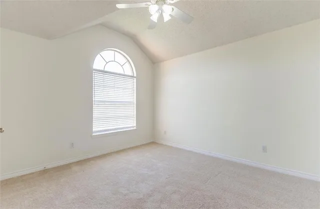 an empty room with a window and a chandelier fan