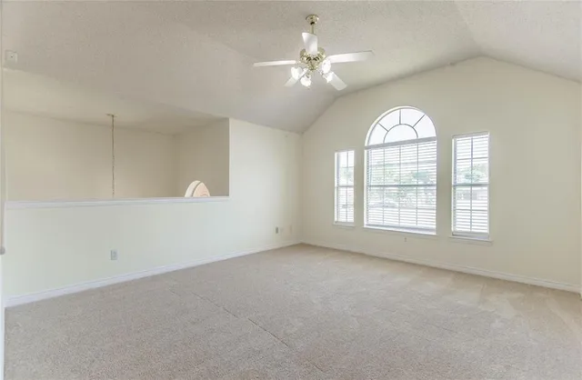 an empty room with windows and chandelier fan