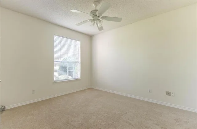 an empty room with a window and a fan